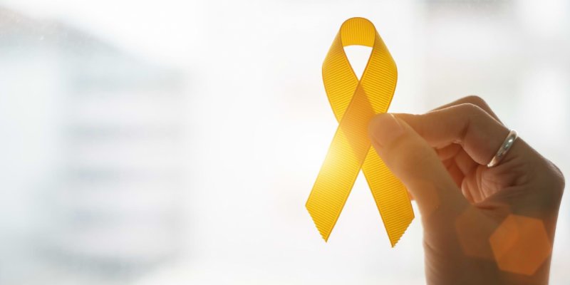 Mão segurando a fita amarela símbolo da prevenção ao suicídio
