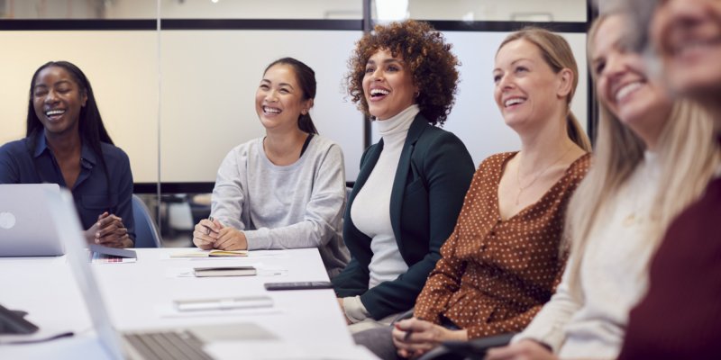 Mulheres em reunião, sorrindo e se comunicando de forma leve