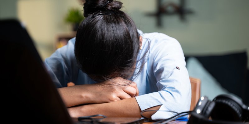 Jovem mulher de negócios dormindo fechando laptop durante o trabalho, conceito de burnout