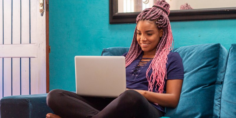A EJA e o Mundo do Trabalho Jovem negra com trança usa um notebook em quarto de casa
